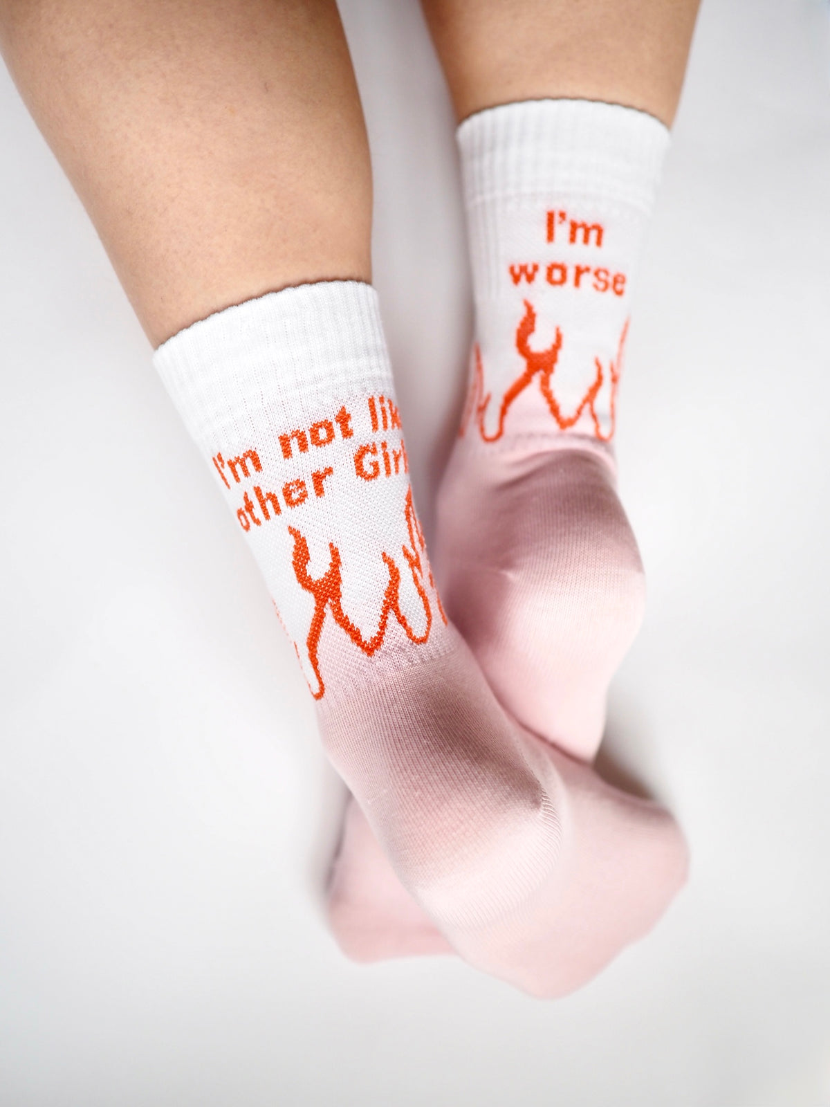 I'm not like other girls / I'm worse -sukat jalassa, tekstit ja oranssit liekit valkoisessa varressa