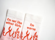 Lähikuva sukkien varsista: tekstit I'm not like other girls ja I'm worse sekä oranssit liekit