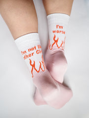 Vaaleanpunaiset sukat valkoisella varrella jalassa, varressa oranssit liekit ja tekstit I'm not like other girls ja I'm worse